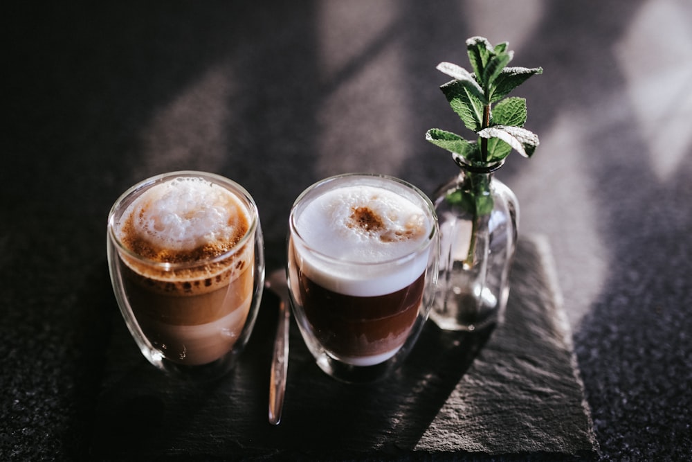 two clear drinking glasses with brown liquid