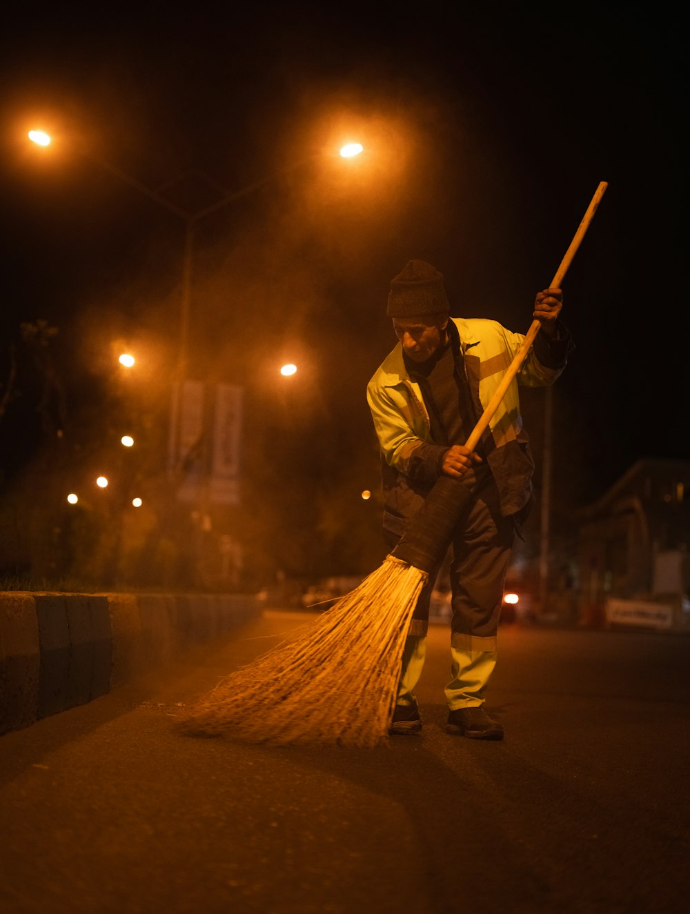 man in yellow jacket holding broom