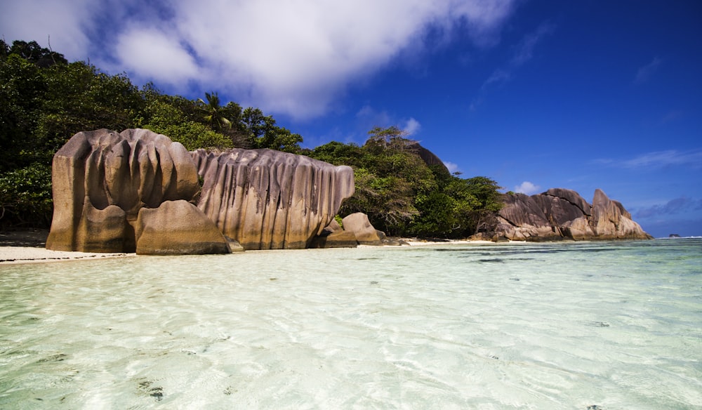 brown rock formation on body of water under blue sky during daytime