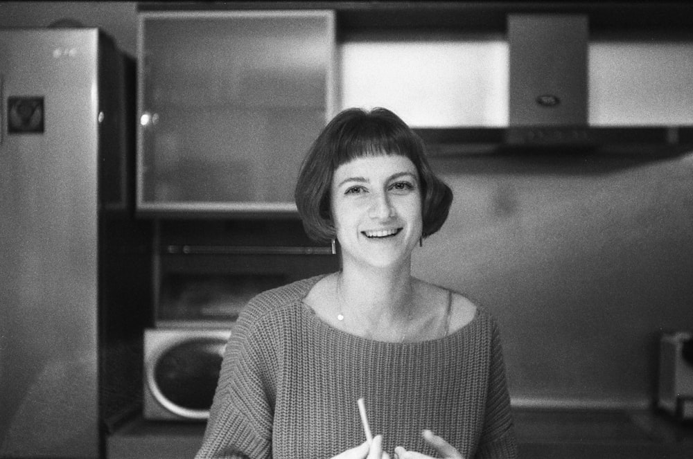 Mujer en suéter sonriendo en fotografía en escala de grises