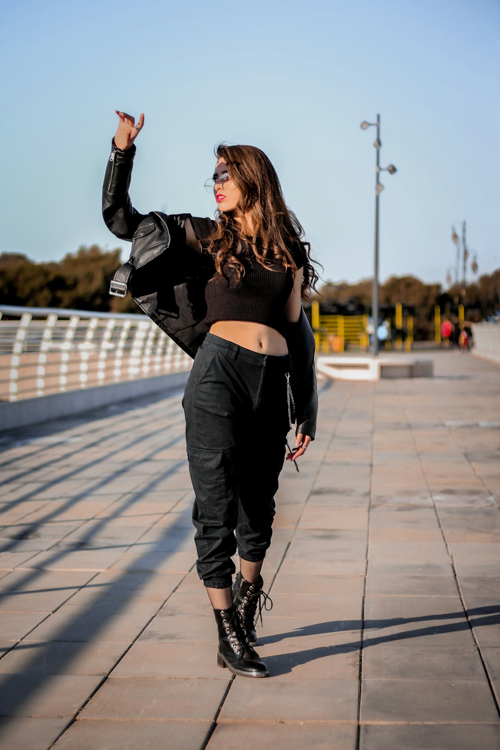 woman in black jacket and gray pants standing on gray concrete pavement during daytime