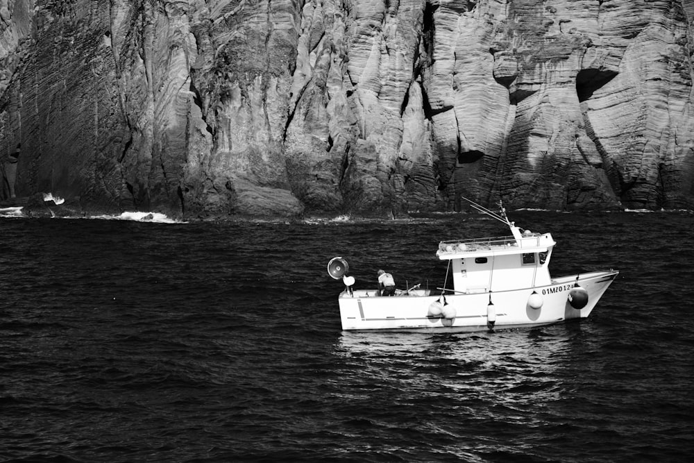 grayscale photo of 2 person riding on boat on body of water