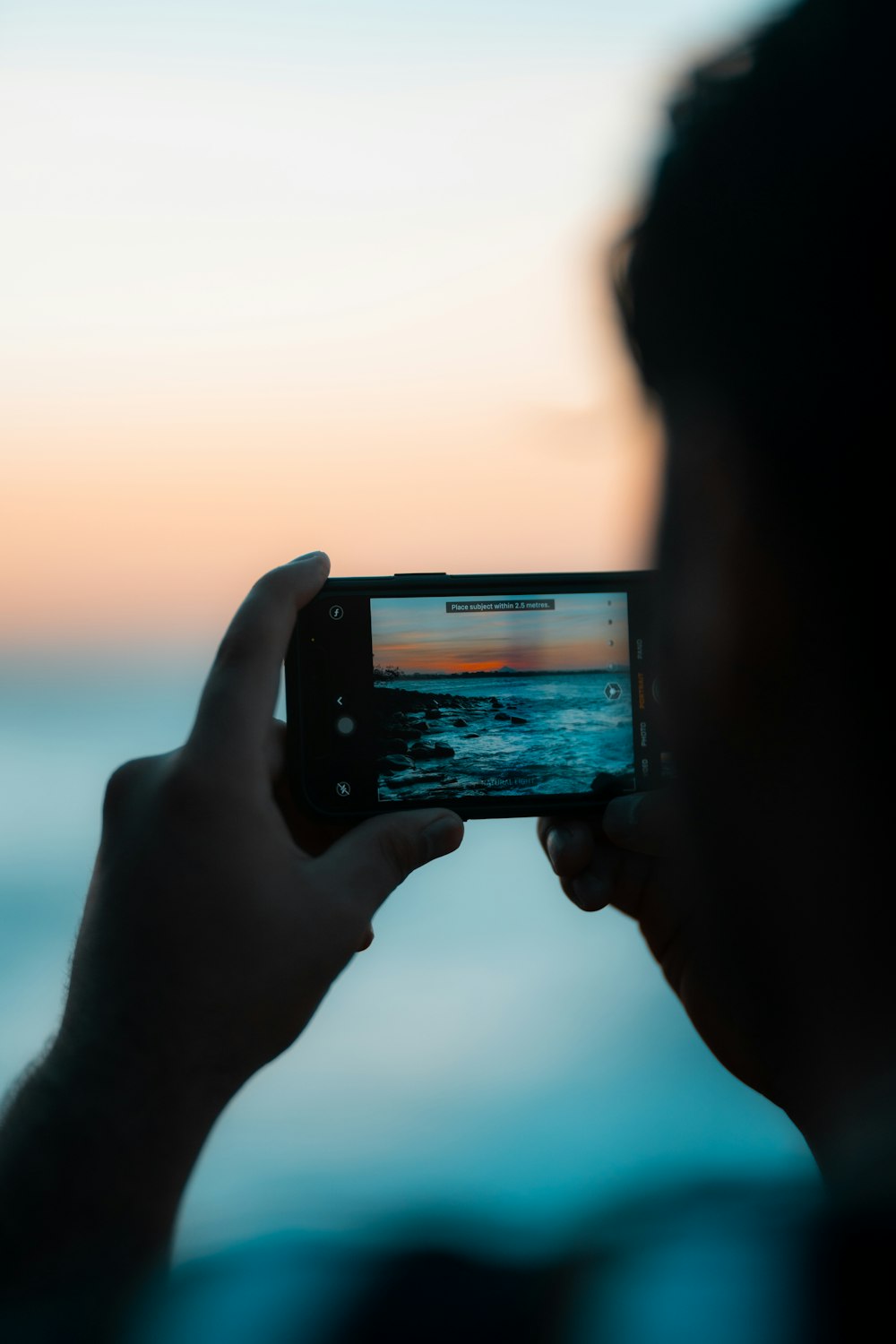 person holding black smartphone taking photo of sunset