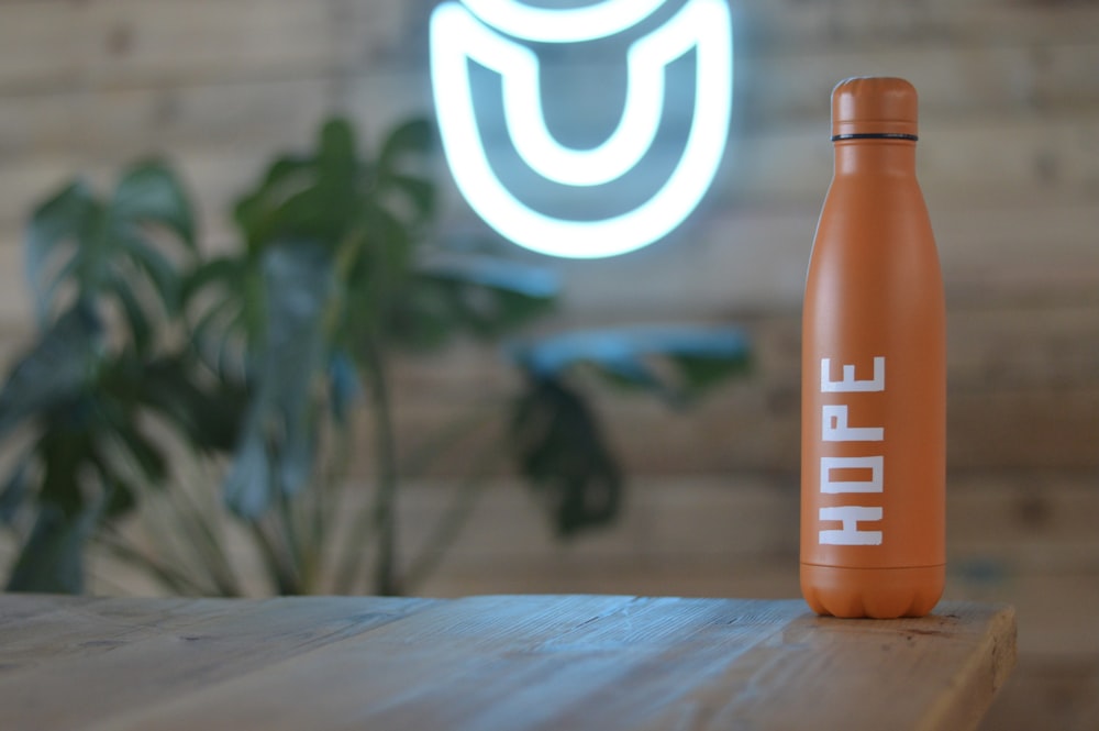 orange-weiße Plastikflasche auf braunem Holztisch