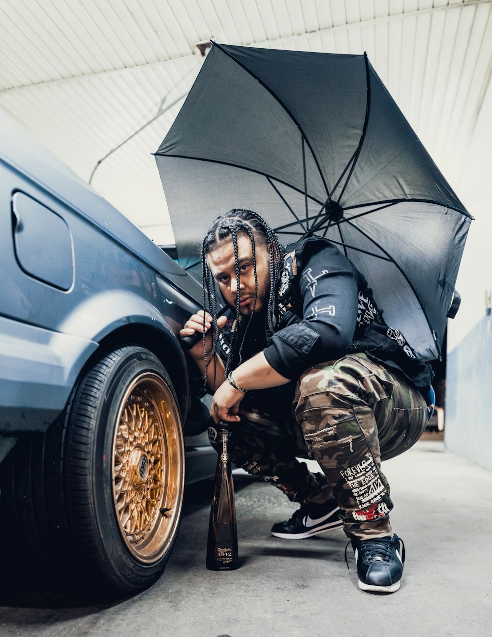 man in green and black camouflage uniform holding umbrella near silver car during daytime