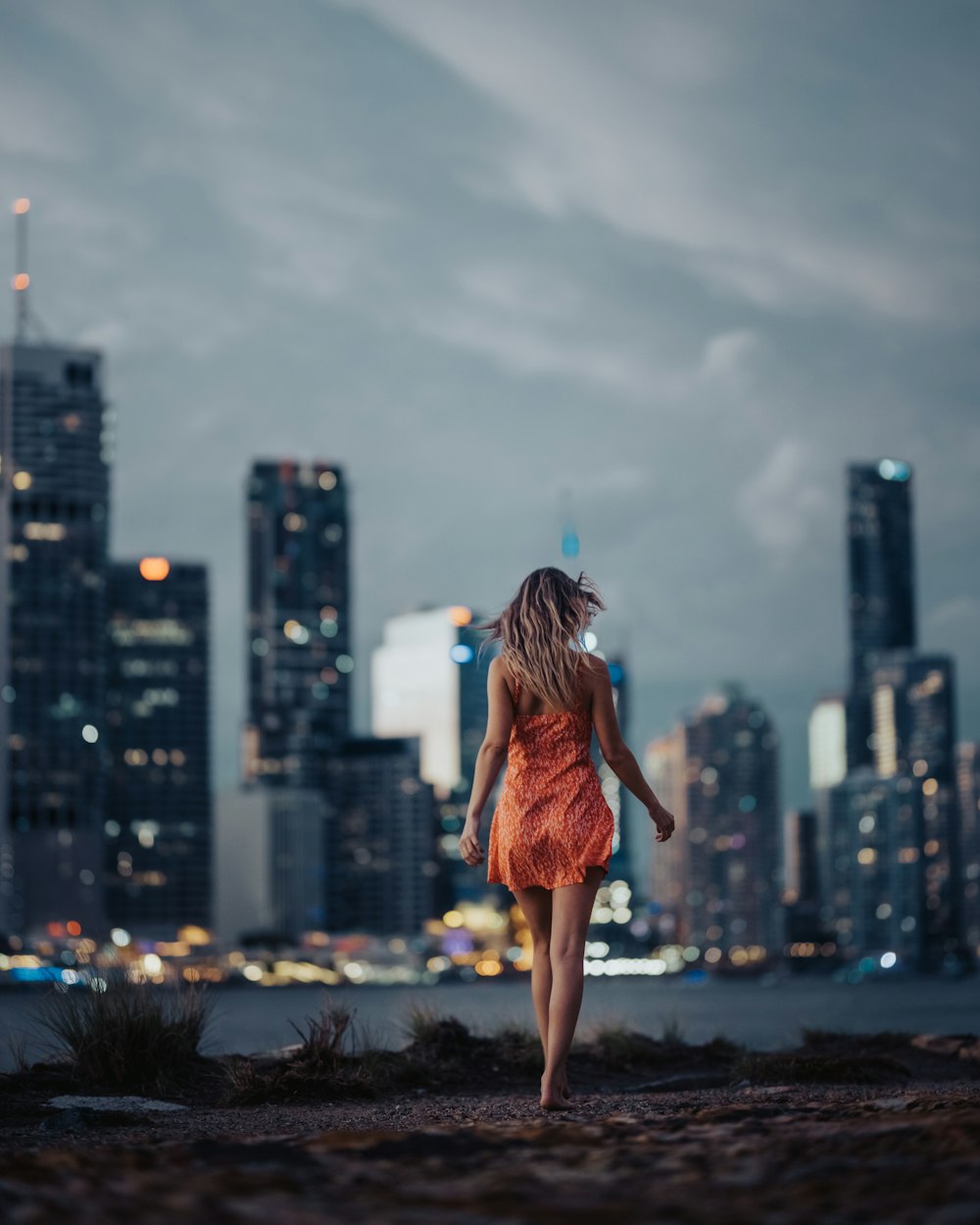 woman in orange dress standing on top of building during daytime