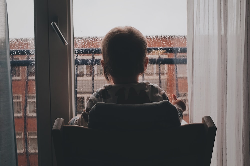 person sitting on chair near window during daytime