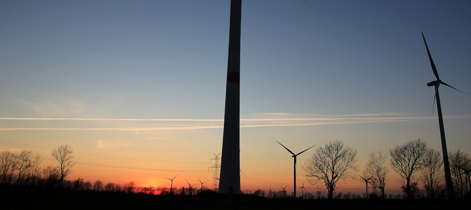 A panoramic view of a wind farm at sunrise, with turbines gently turning against a colorful sky.