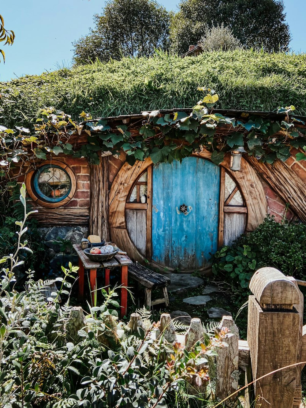 Casa de madera marrón con plantas y árboles verdes