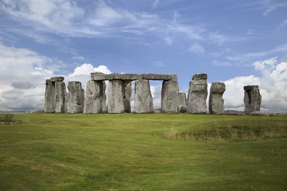 gray rock formation on green grass field under blue sky during daytime