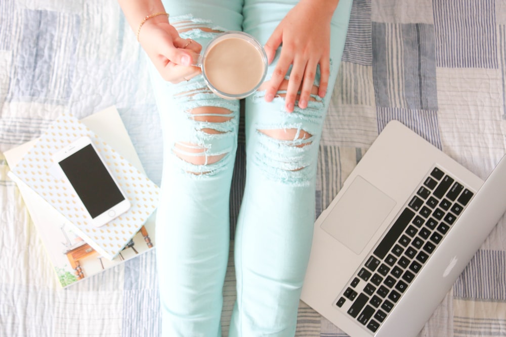 Persona en jeans de mezclilla azul sosteniendo una taza de cerámica blanca