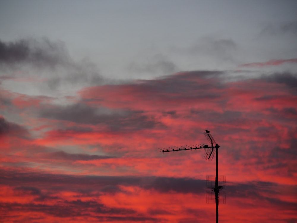 silhouette of wind turbines under orange and gray cloudy sky