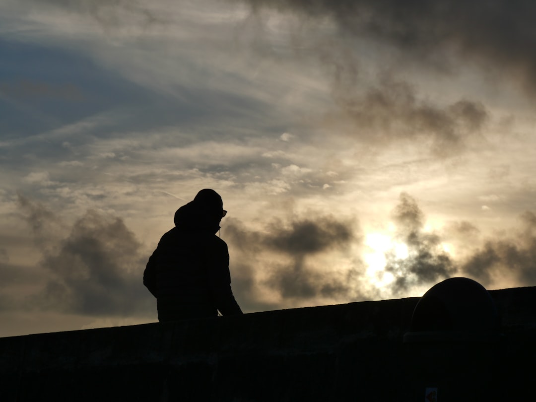 silhouette of man standing on top of building under cloudy sky
