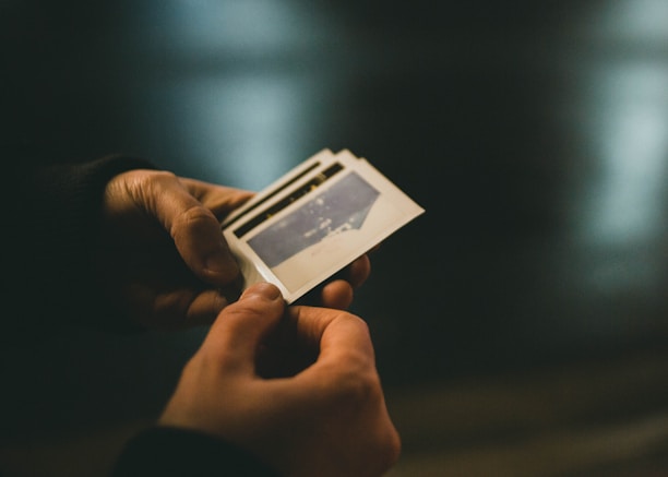 Close-up of a hand holding a freshly printed photo strip with smiling faces from a recent event.