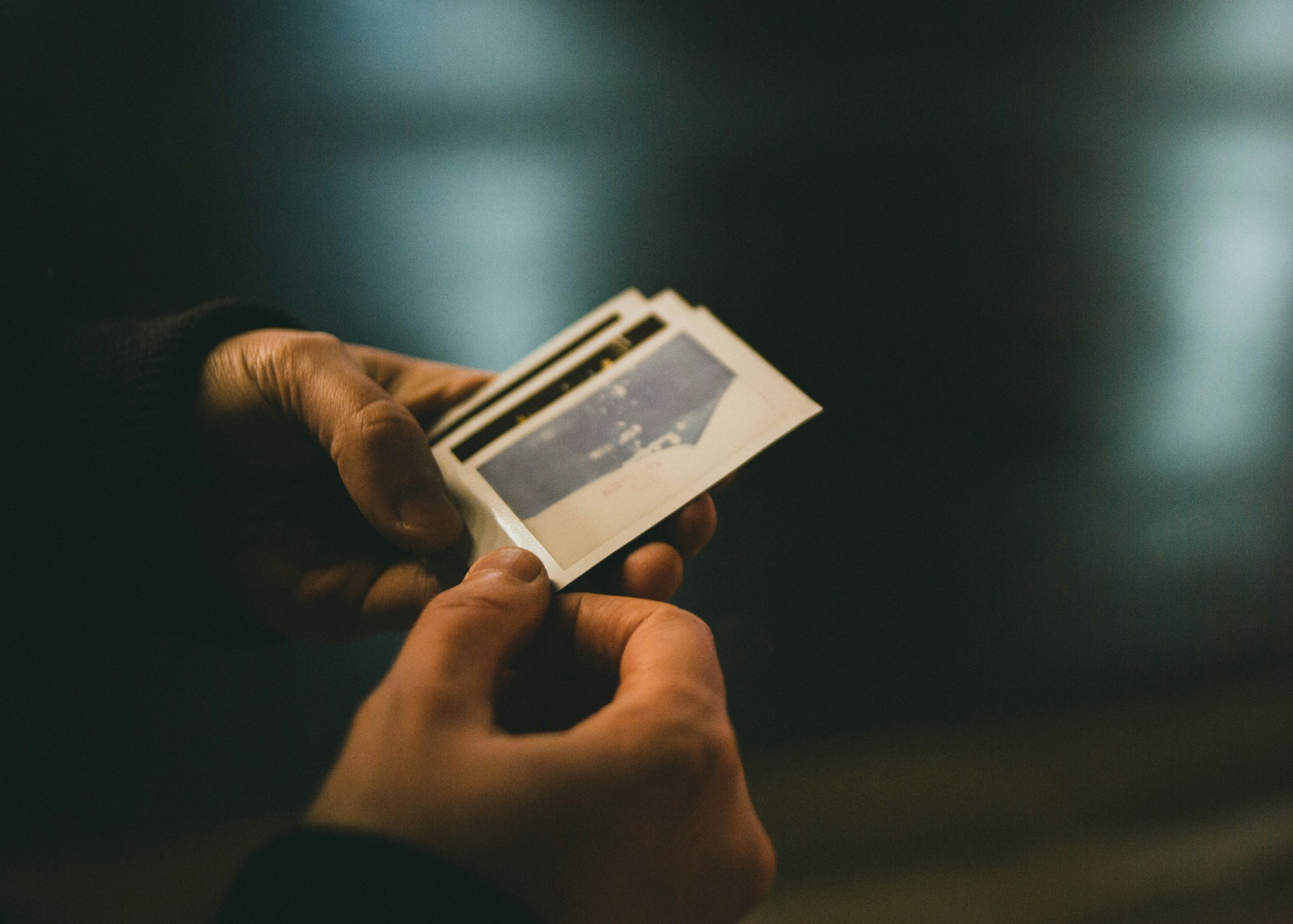 Close-up of hands holding a freshly printed photo strip from the booth, showcasing genuine smiles and candid expressions.