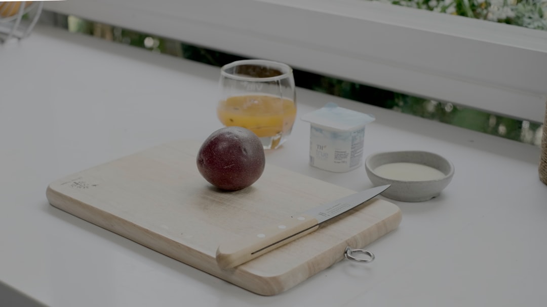 apple fruit beside clear drinking glass on white wooden table