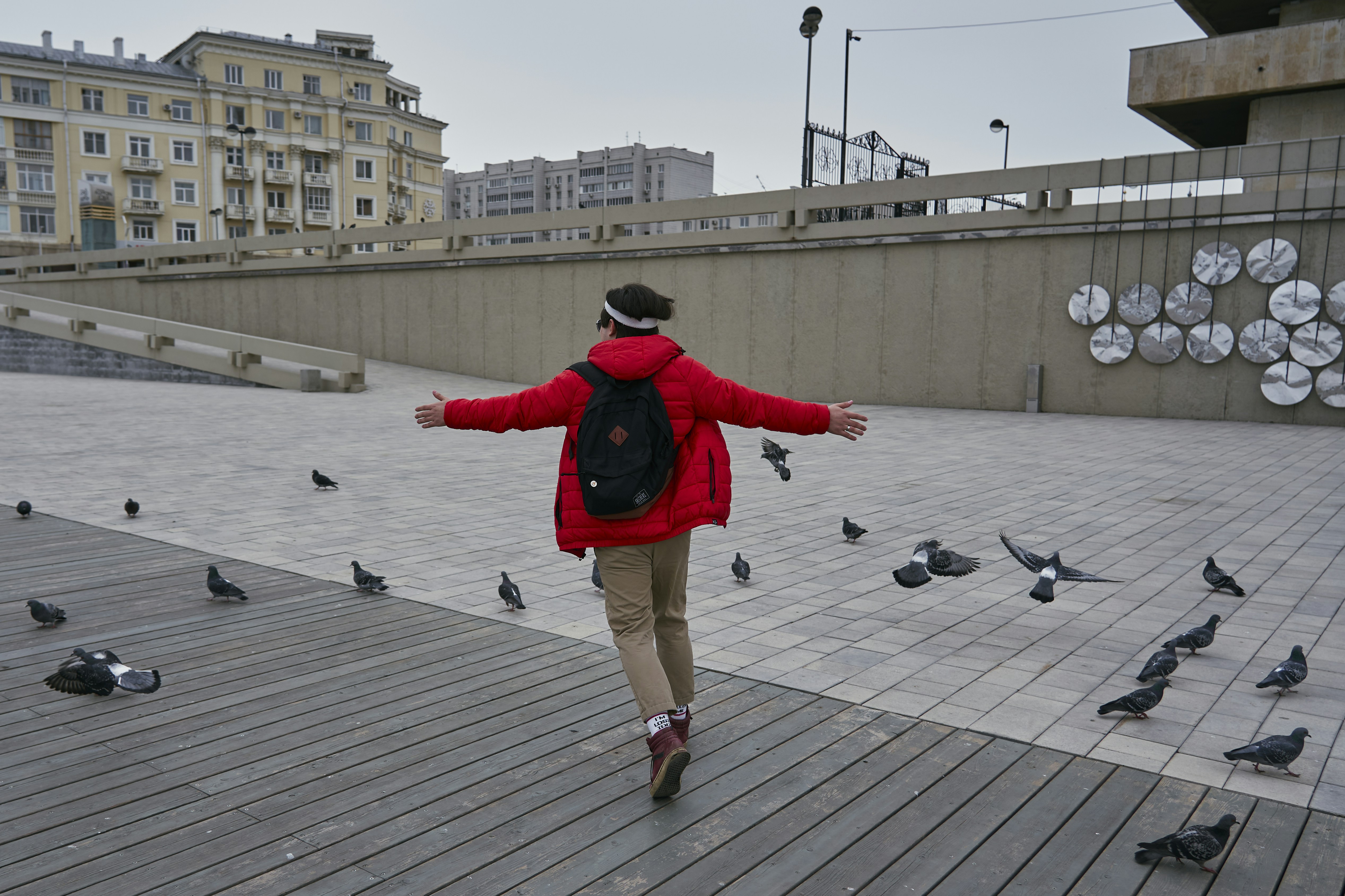 man in red and black jacket and brown shorts walking on gray wooden dock during daytime