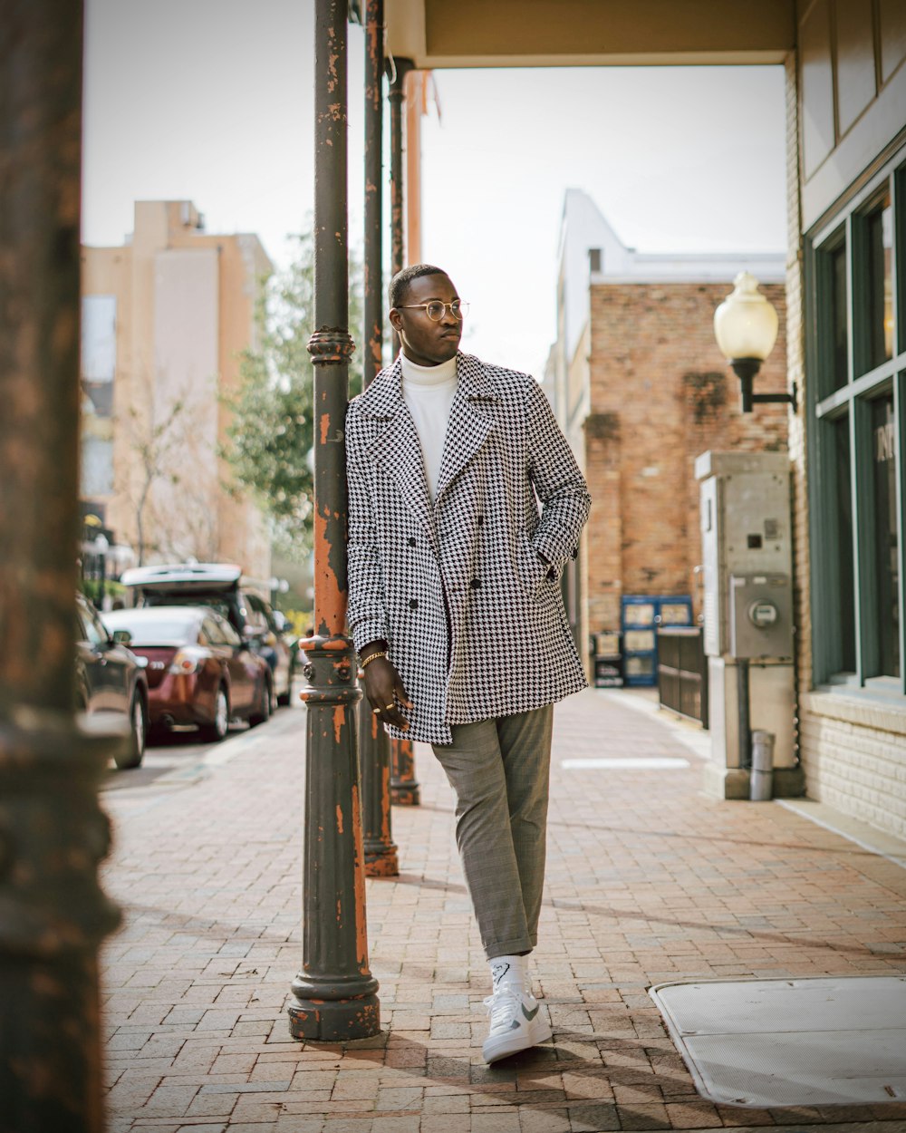 man in white and red checkered dress shirt standing on sidewalk during daytime