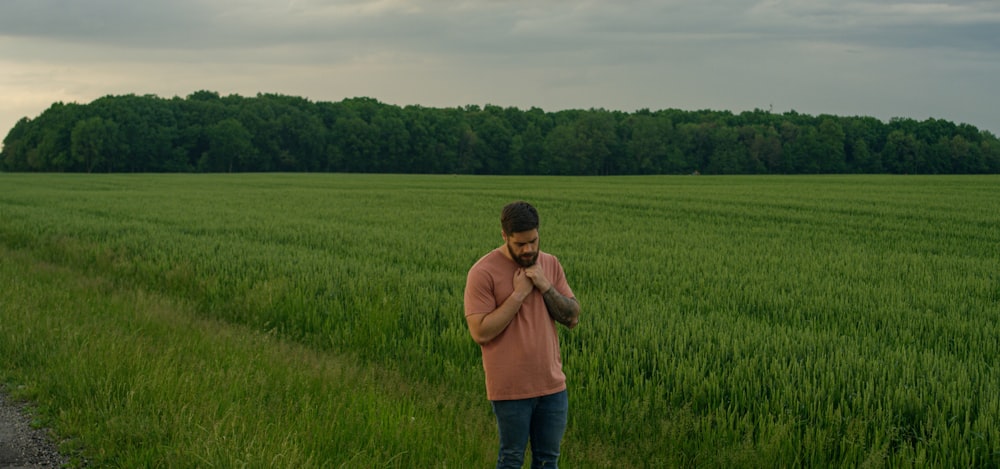 man in brown long sleeve shirt and blue denim jeans standing on green grass field during