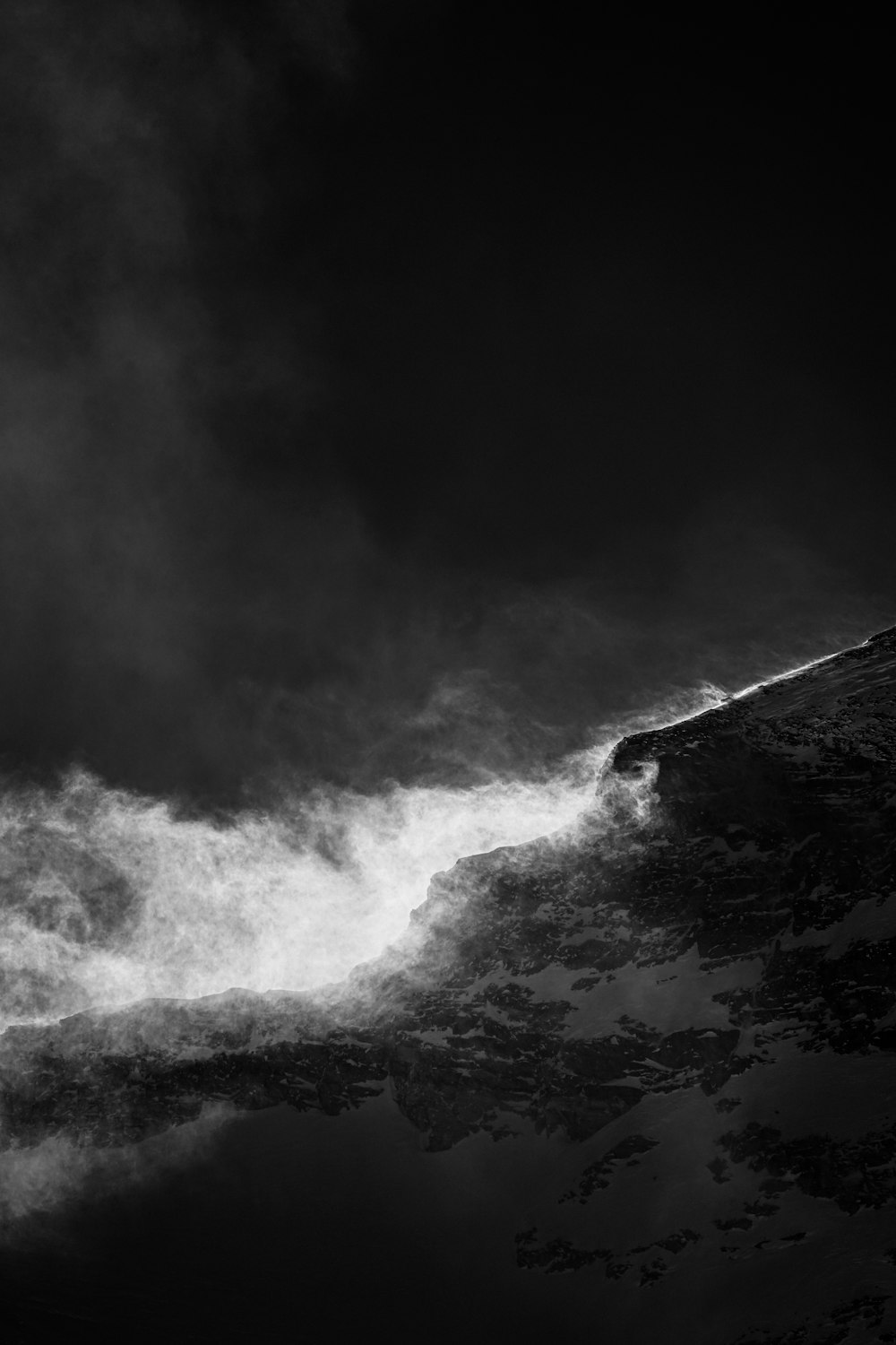 grayscale photo of mountain under cloudy sky