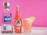 A bottle of 1800 Silver Tequila stands next to a Jarritos guava soda bottle, both placed on a marble surface. Beside them, a glass filled with a pink beverage, topped with coconut shavings and garnished with a lime slice. The background is a vibrant pink.