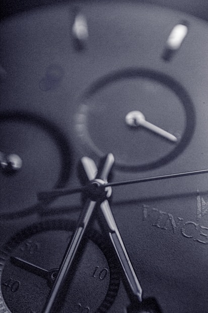 Close-up view of a sophisticated watch face, highlighting the precision of its hands and dials with a sleek, metallic finish.