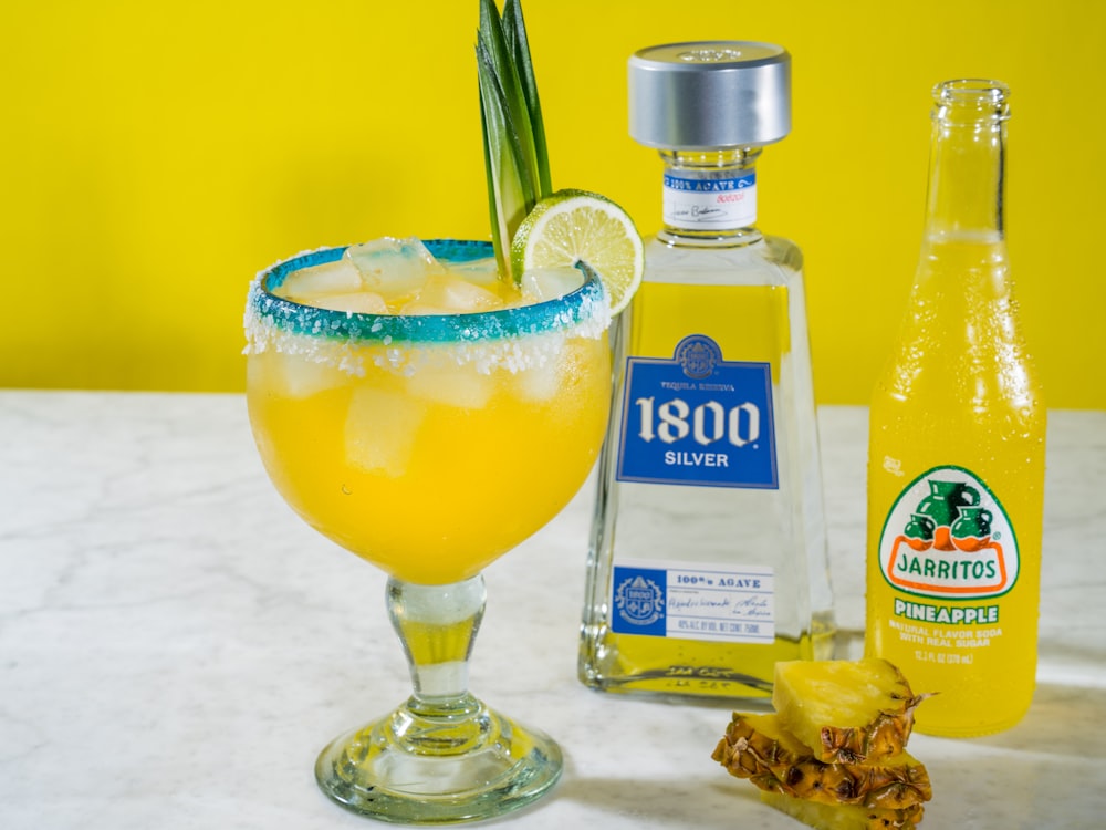 clear glass bottle beside clear glass cup with yellow liquid