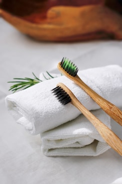 Close-up of bamboo toothbrushes and wooden combs arranged neatly on a rustic wooden table.