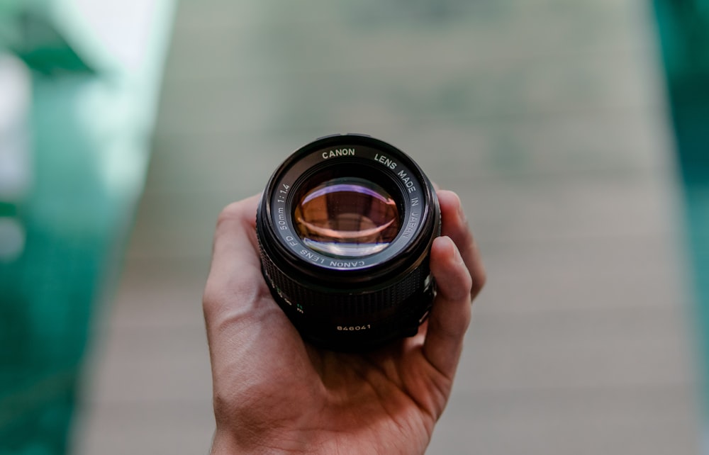 person holding black camera lens