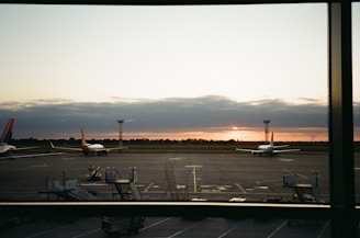 A serene sunrise over a bustling airport runway, with planes ready for takeoff.