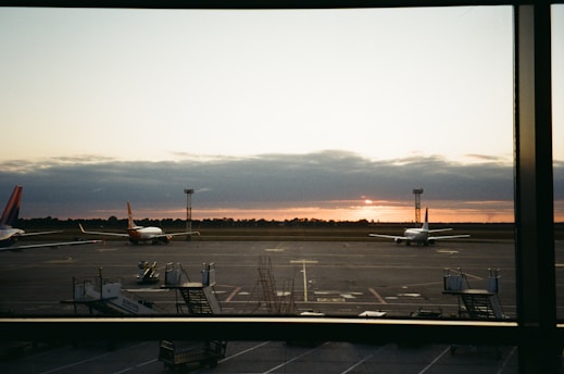A serene sunrise over a bustling airport runway, with planes ready for takeoff.