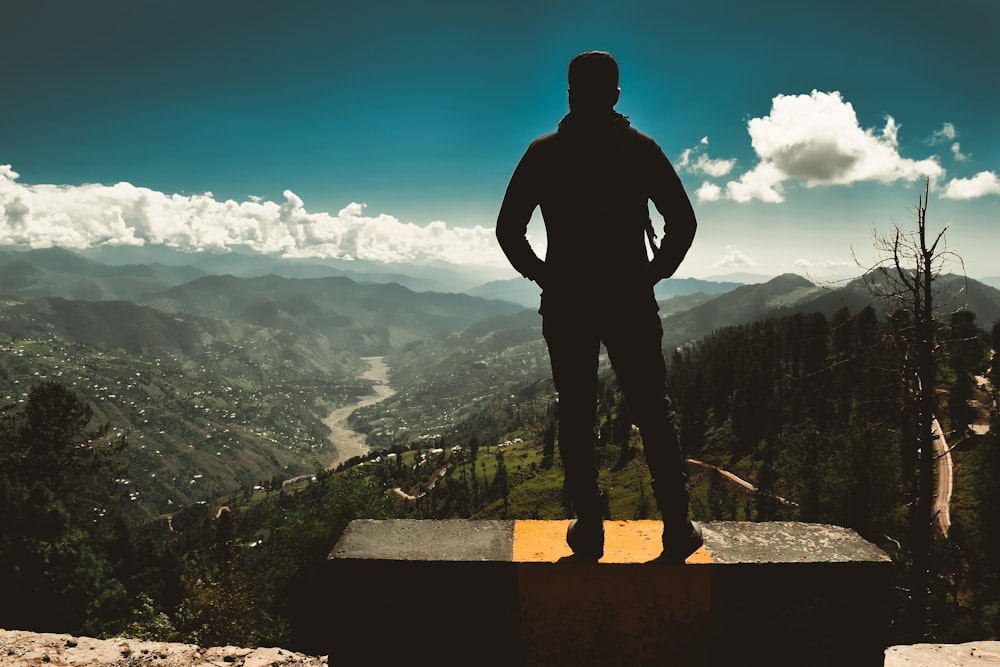 silhouette of man standing on rock formation during daytime