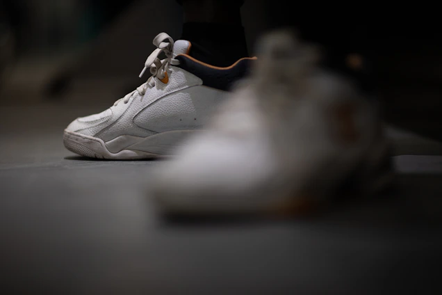 A close-up shot of a fresh pair of sneakers resting on a wooden floor with soft natural light highlighting their details.