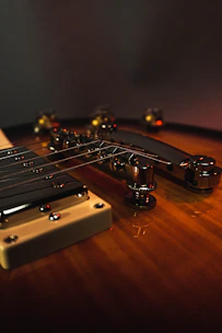 Close-up of a handcrafted Stratocaster guitar with rich wood grain and dramatic lighting highlighting its premium finish.