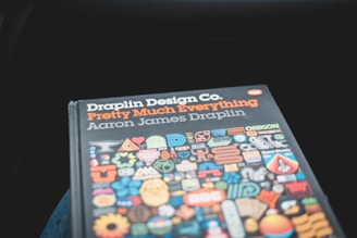 A book cover titled 'Draplin Design Co. Pretty Much Everything' by Aaron James Draplin. The cover features various colorful icons and symbols arranged in a grid pattern below the title.