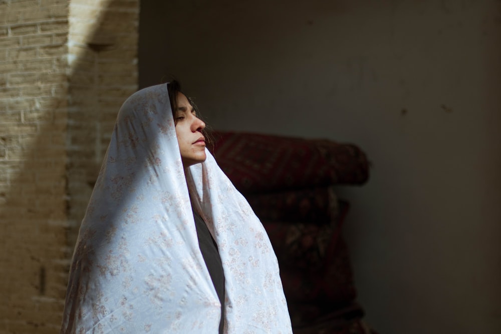 woman in white hijab covering her face with white textile