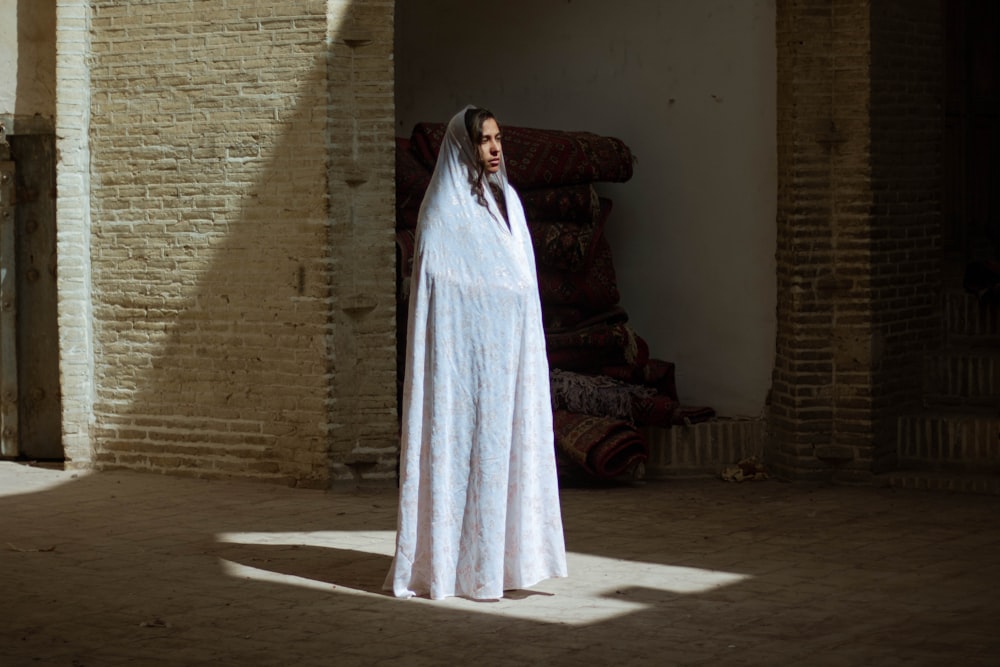 woman in white dress standing near brown sofa