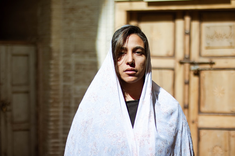 woman in white hijab standing near brown wall