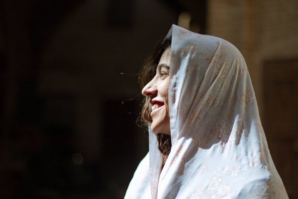 Femme en hijab blanc couvrant son visage avec un textile blanc
