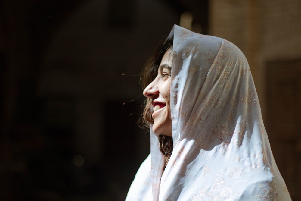 woman in white hijab covering her face with white textile