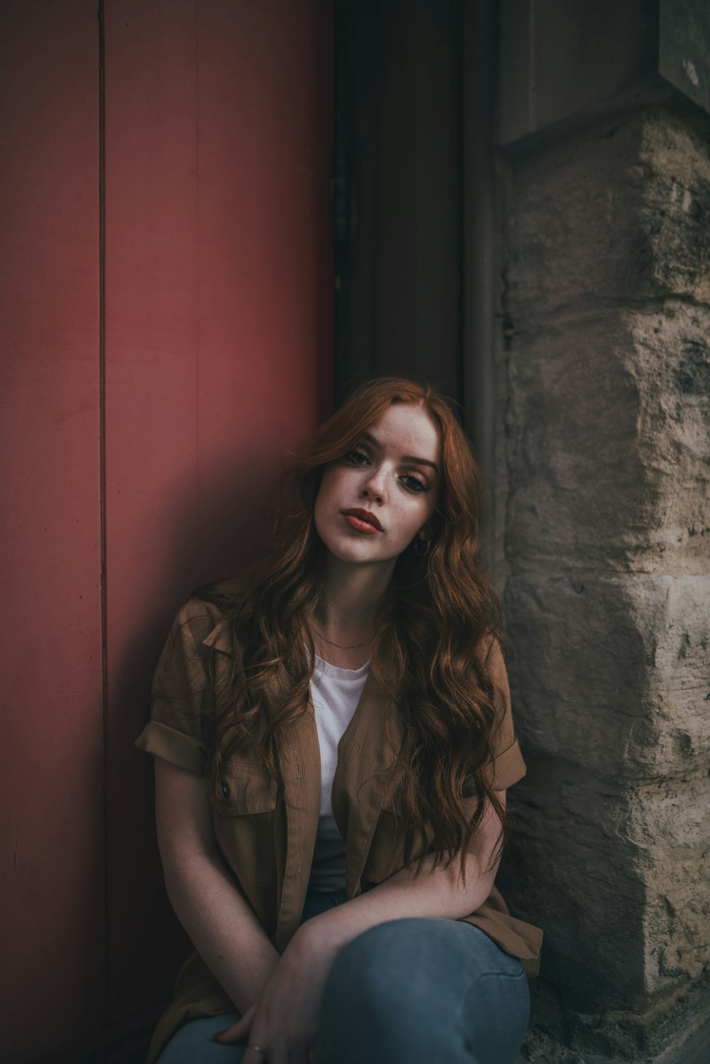 woman in brown button up shirt standing beside red wooden door