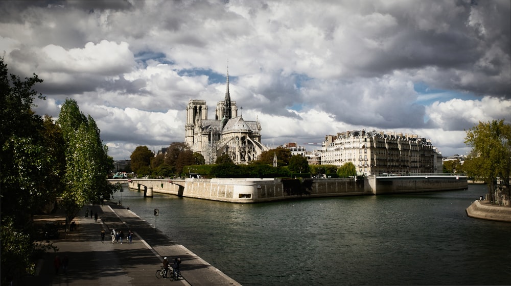 white concrete building near body of water under cloudy sky during daytime