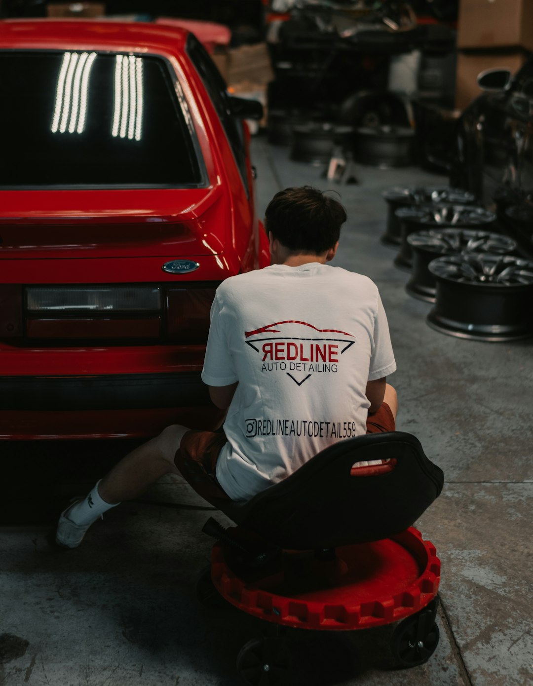 man in white crew neck t-shirt sitting on red car