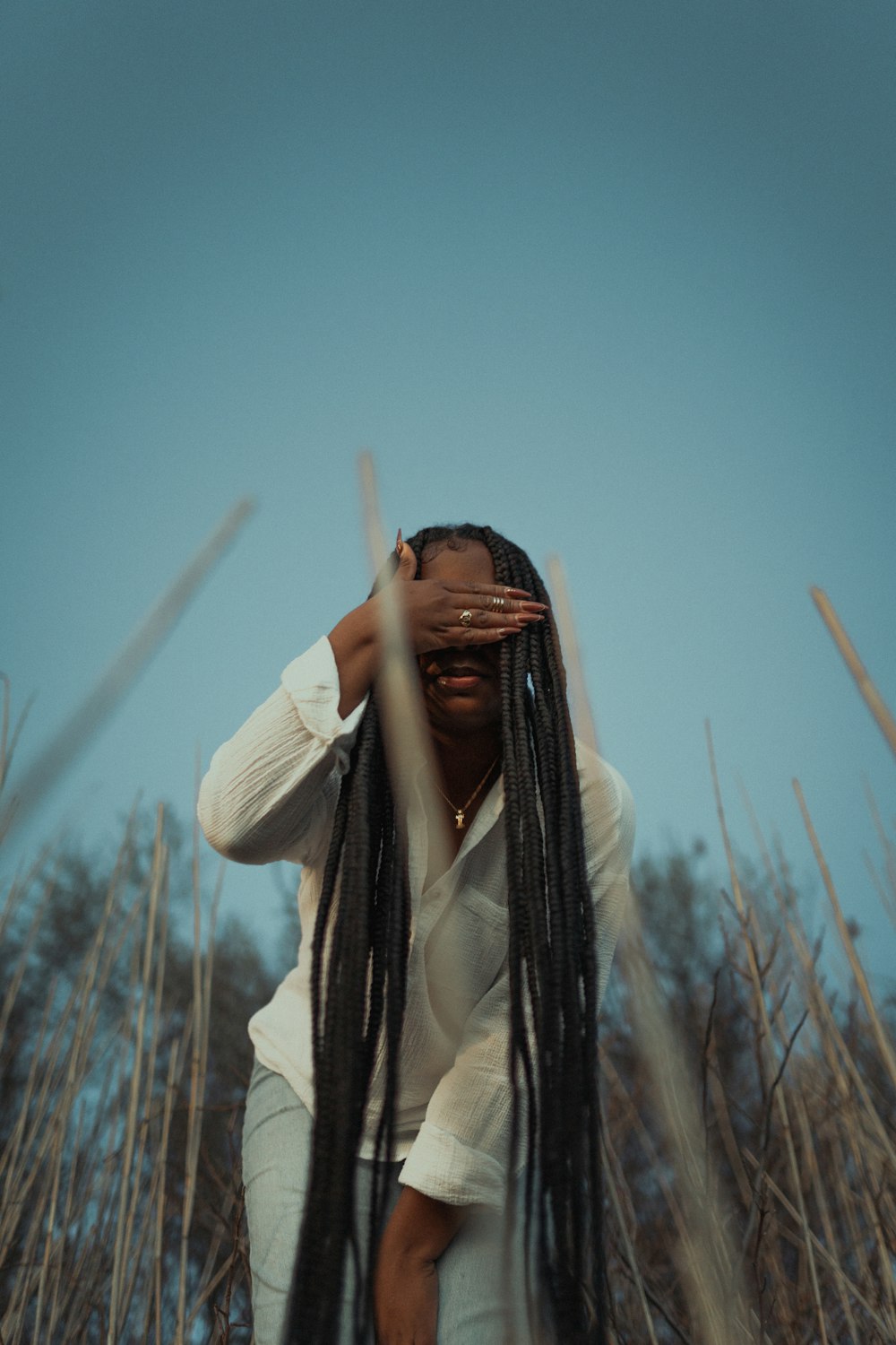 woman in white long sleeve shirt covering her face with her hands