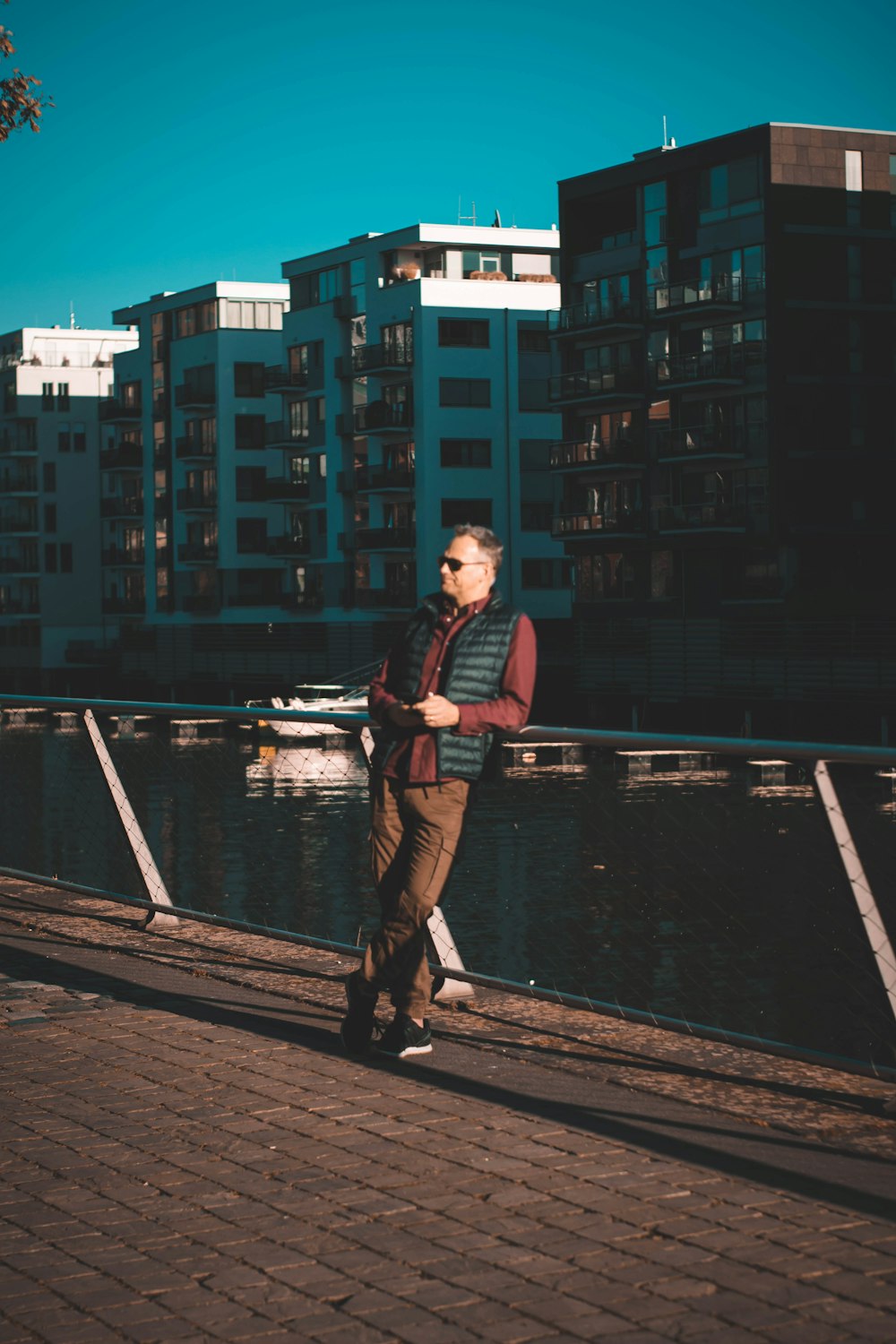 man in black and red plaid dress shirt and brown pants standing on wooden dock during