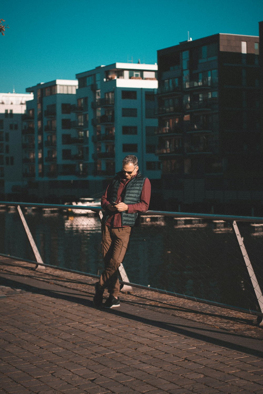 man in black jacket and blue denim jeans standing on bridge during daytime