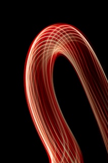 An abstract animation featuring smooth flowing curves in black, white, and metallic silver tones with glowing light streaks.