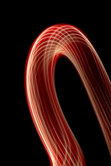 An abstract animation featuring smooth flowing curves in black, white, and metallic silver tones with glowing light streaks.