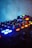 A close-up view of a sound mixing console with various knobs and buttons illuminated in blue and orange lights. The background is blurred, creating a focus on the equipment with an atmospheric and moody lighting setup.