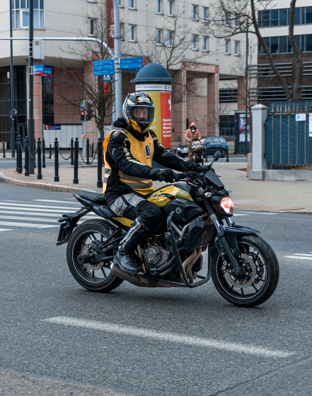 man in yellow helmet riding black sports bike on road during daytime